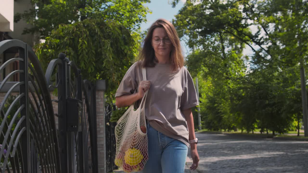 一名妇女用可重复使用的细绳袋携带食品杂货