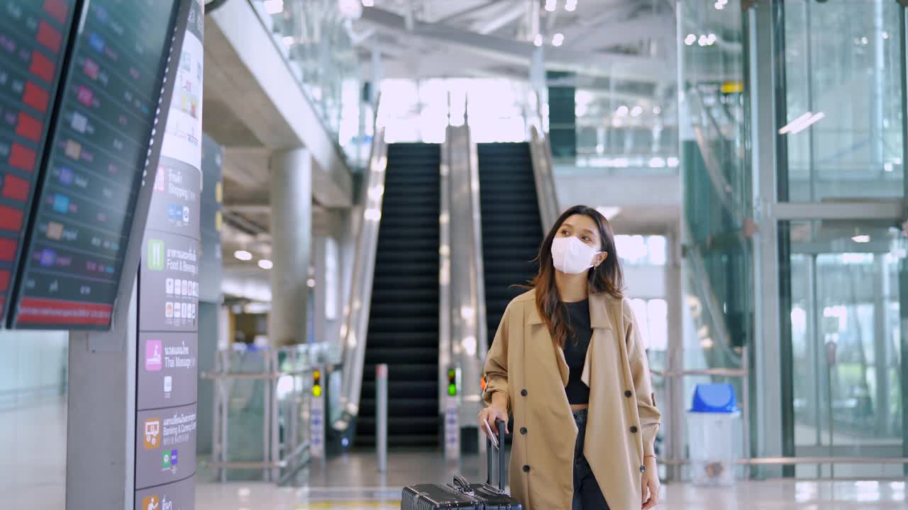 旅客在机场戴着口罩看航班时刻表。