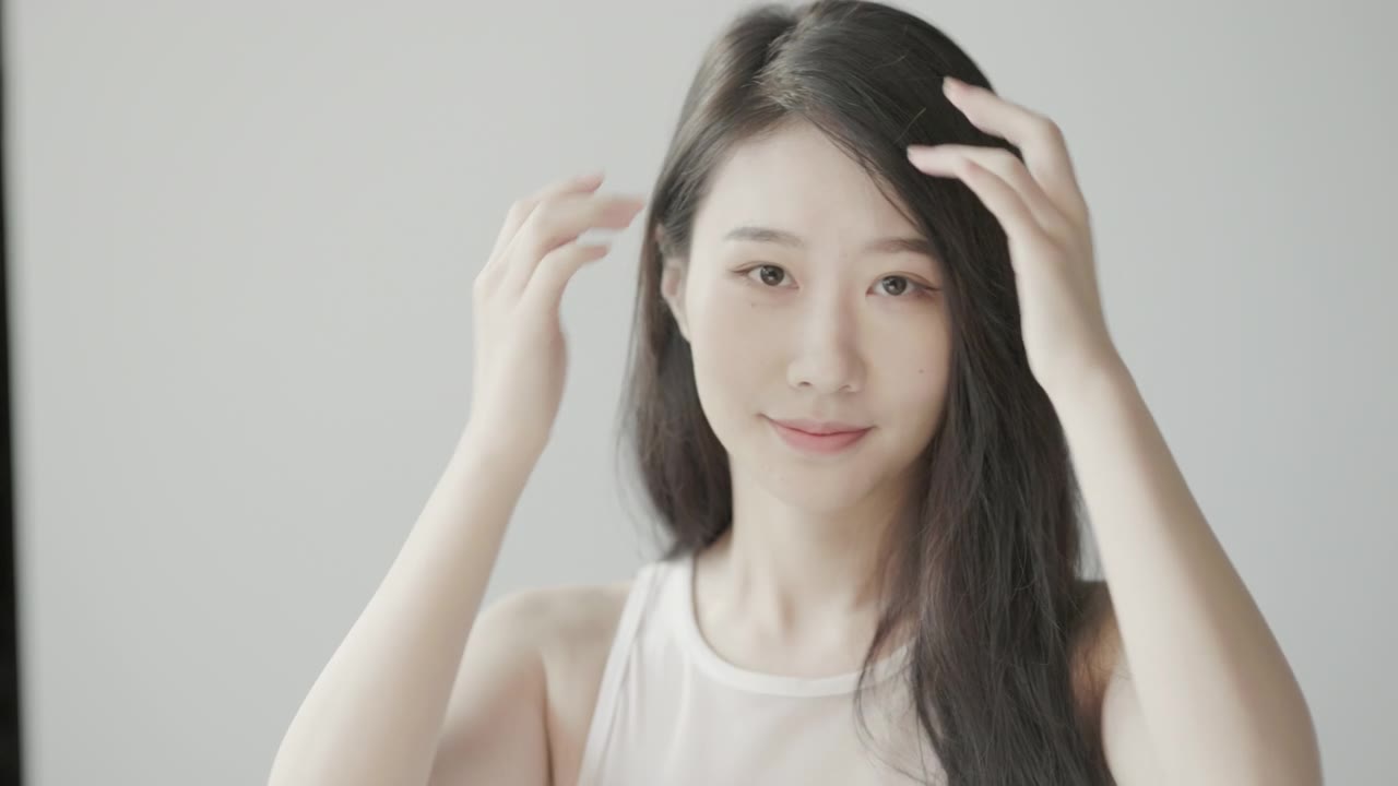 詳情圖-美麗的年輕亞洲女人與長長的黑色頭發(fā)，看著鏡子和拍攝慢動(dòng)作在一個(gè)明亮的房間