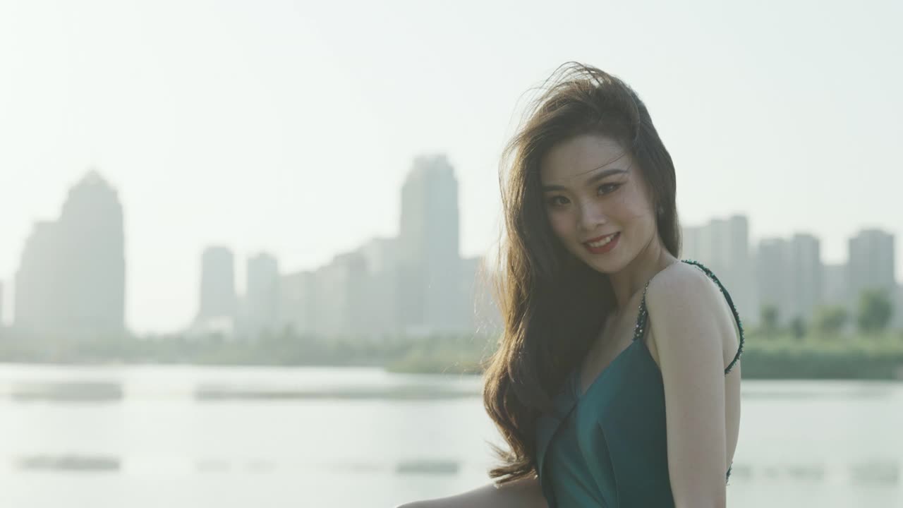 一位身穿绿色晚礼服的亚洲美女站在中央公园的湖边