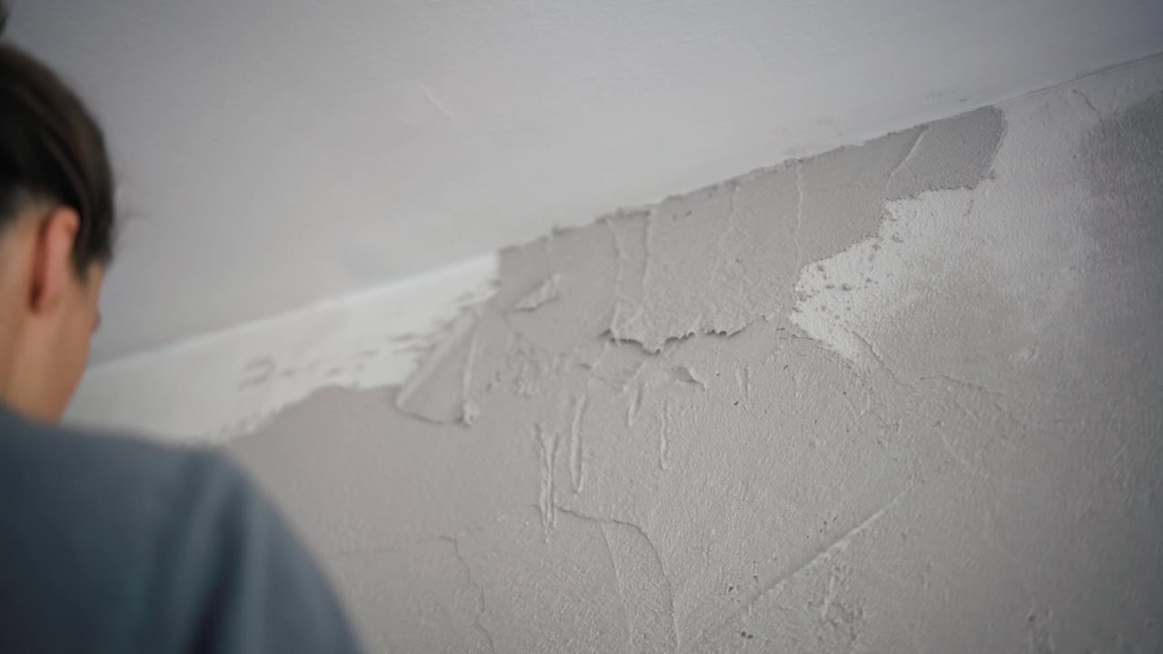 一位专业的修理工用抹刀在墙上抹灰泥。