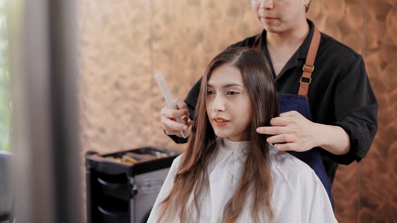 亚洲专业发型师正在美容院为顾客理发。有吸引力的美丽的亚洲妇女坐和等待剪新发型。