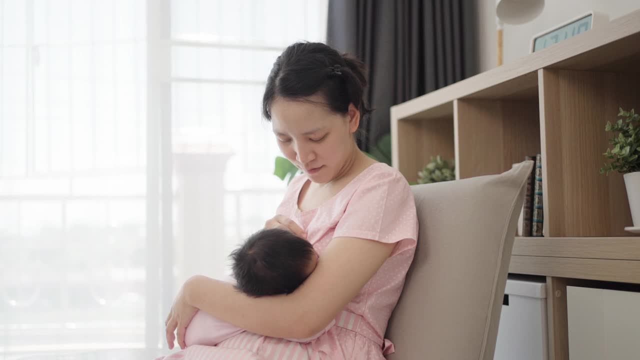 年轻的亚洲母亲正在哺乳她的孩子。