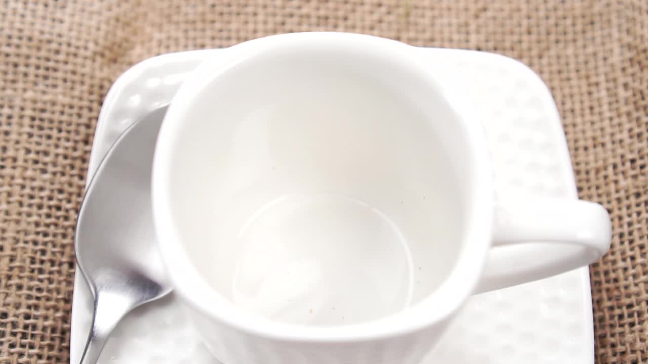 天然有机健康饮品配料从茶匙中倒入白色茶杯中