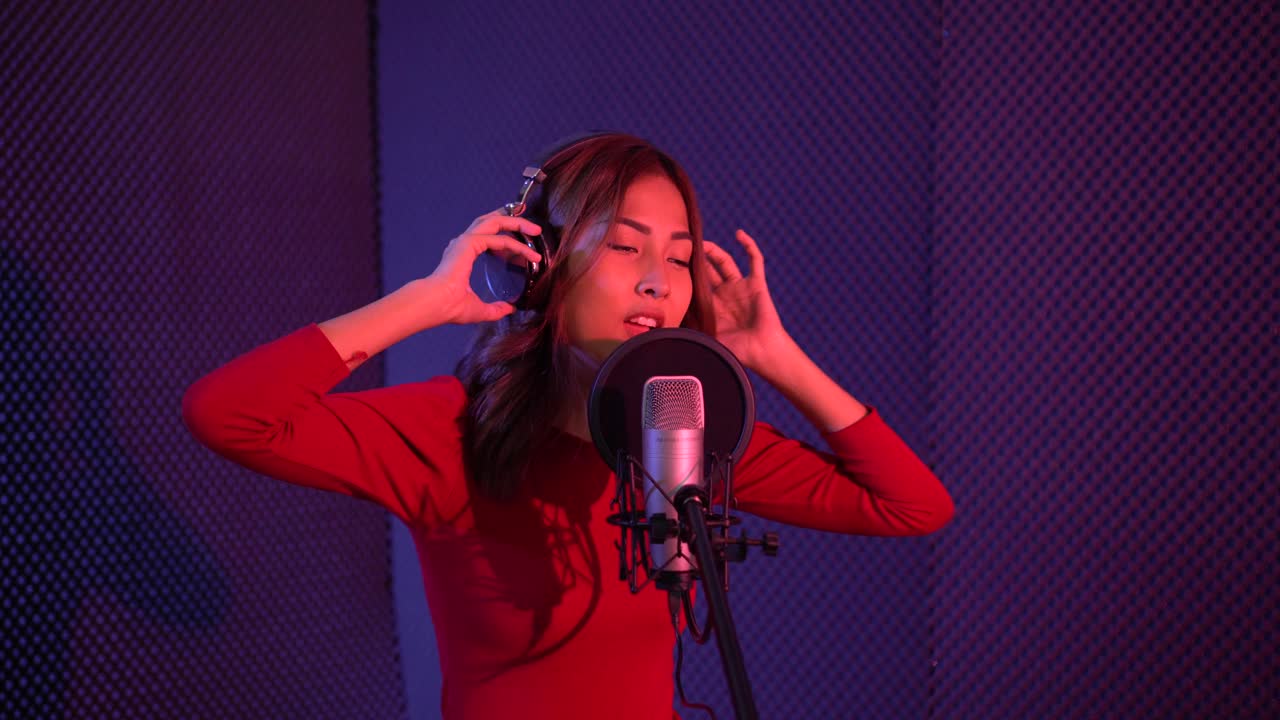 一位美丽的亚洲女歌手正在录音室练习唱歌。