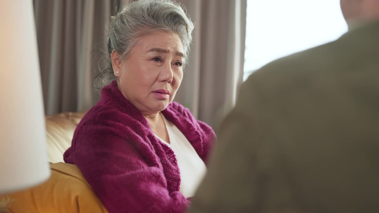 幸福亚洲成年退休女性休闲服饰放松坐在沙发沙发上与家人聊天交谈假期周末客厅，亚洲老年女性与家人良好的关系留在家里呆在家里