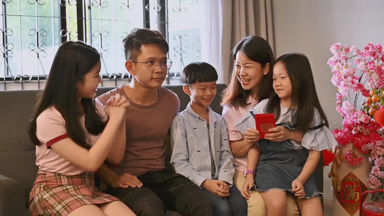 春节期间，一个亚洲小孩在客厅里接受父母的春节红包。