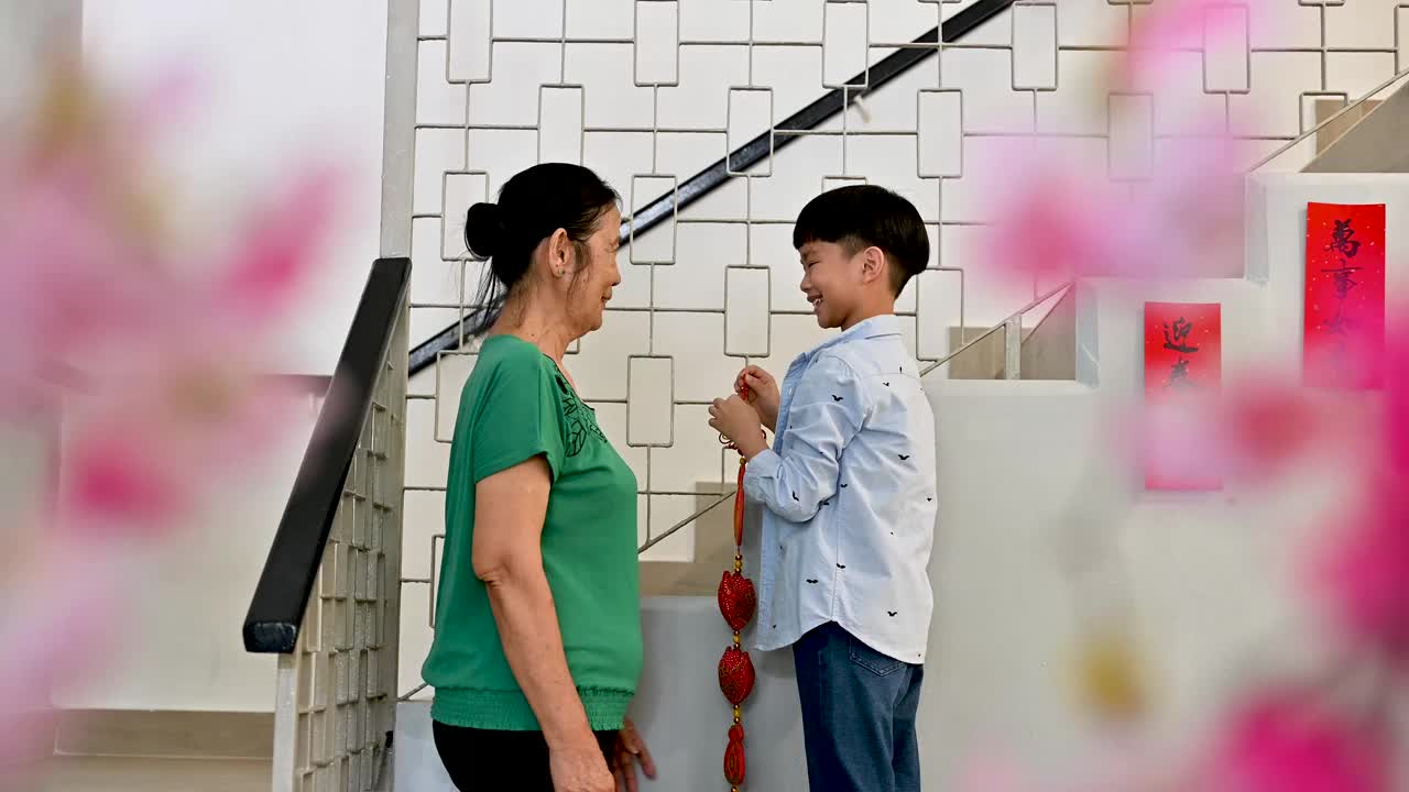 快乐的奶奶和小孙子一起装饰他们的房子过中国新年
