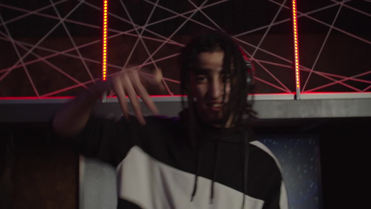 带耳机的精力充沛的酷dj的肖像在夜总会现场为人们加油