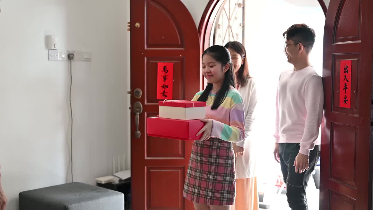 年轻漂亮的亚洲少女和父母在中国新年期间拜访她的亲戚家，赠送礼物和食物