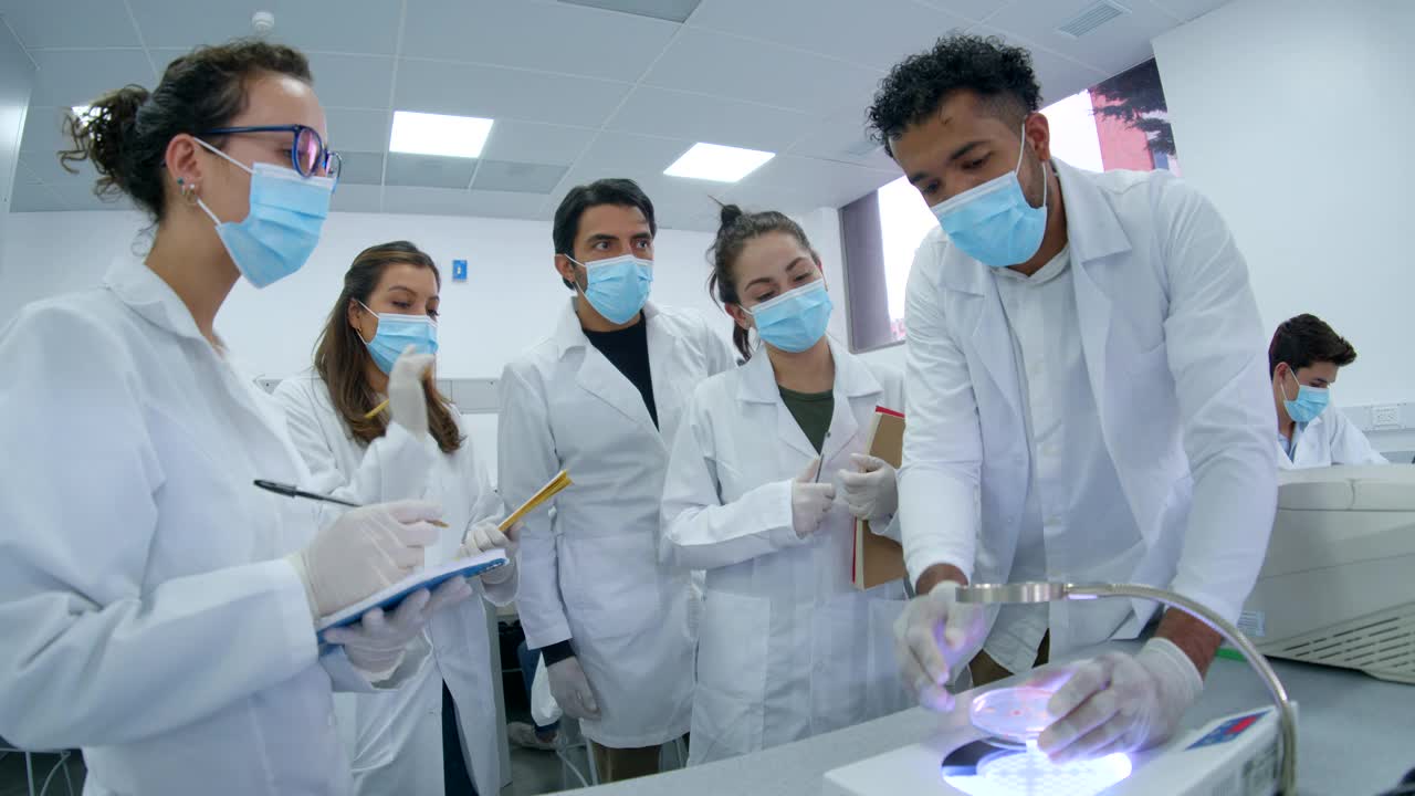细菌学课上，一群拉丁美洲学生正在听老师展示放大镜下的样本