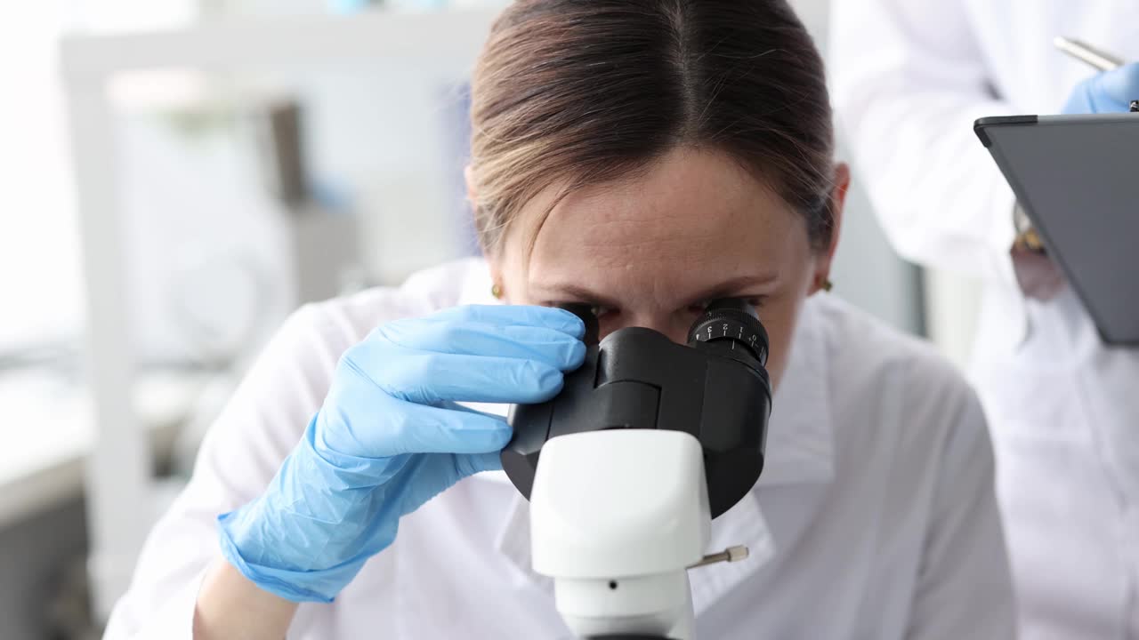 女生物学家在实验室里通过显微镜看4k电影