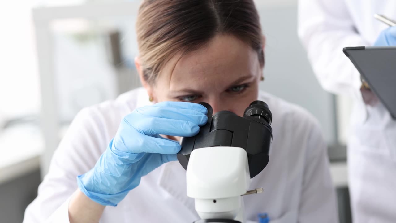 详情图-女生物学家在实验室里通过显微镜看4k电影