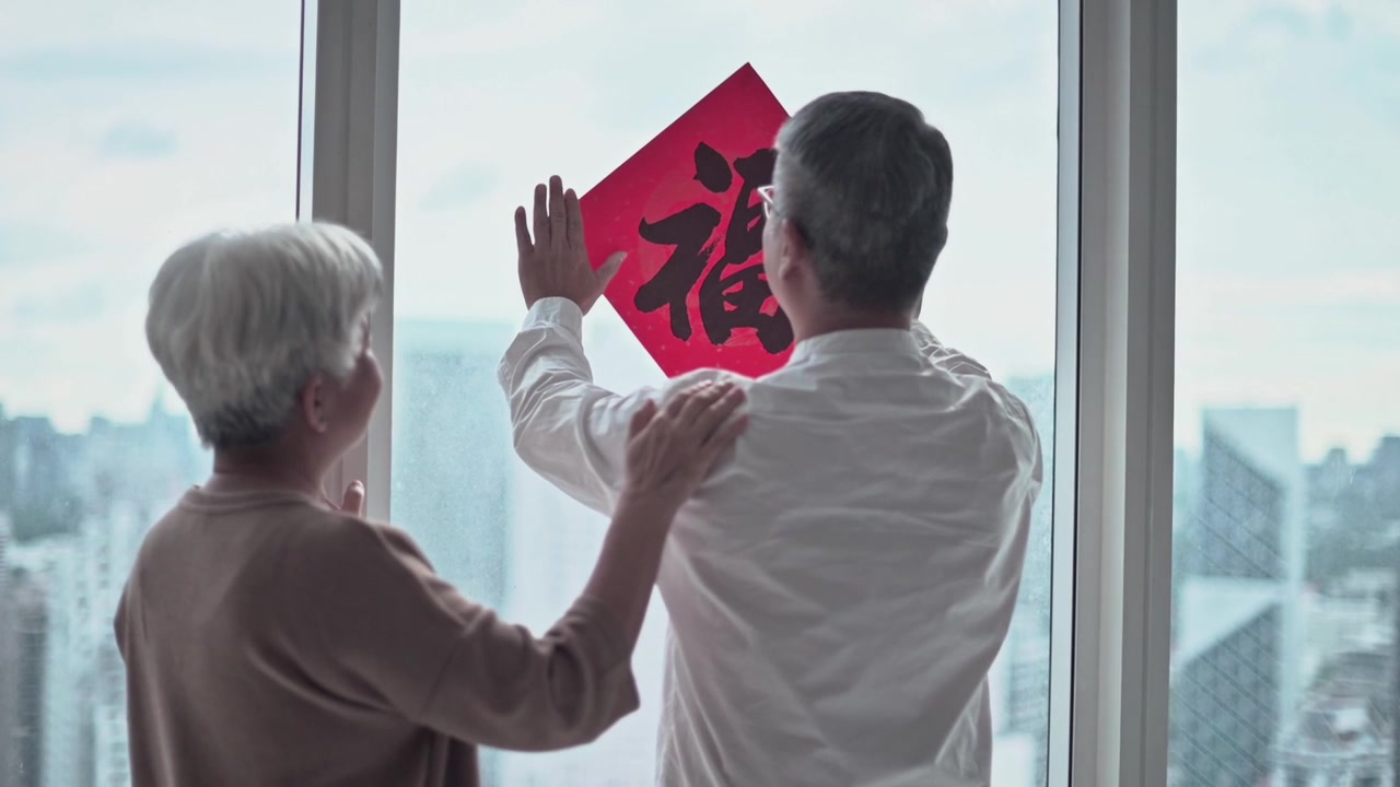 詳情圖-中國(guó)新年老夫婦裝飾房子的客廳，窗戶上的中國(guó)書法裝飾，準(zhǔn)備家庭團(tuán)聚