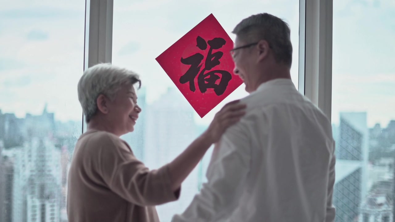 詳情圖-中國(guó)新年老夫婦裝飾房子的客廳，窗戶上的中國(guó)書法裝飾，準(zhǔn)備家庭團(tuán)聚