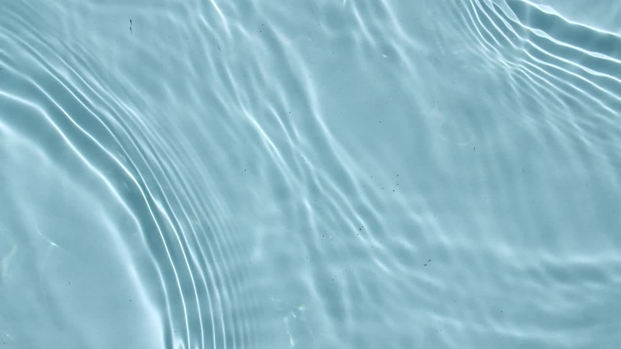 水面紋理俯視圖。水濺起藍(lán)色。純凈的藍(lán)色海水以慢動(dòng)作反射陽(yáng)光。陽(yáng)光和陰影。運(yùn)動(dòng)清潔游泳池的漣漪和波浪。4 k