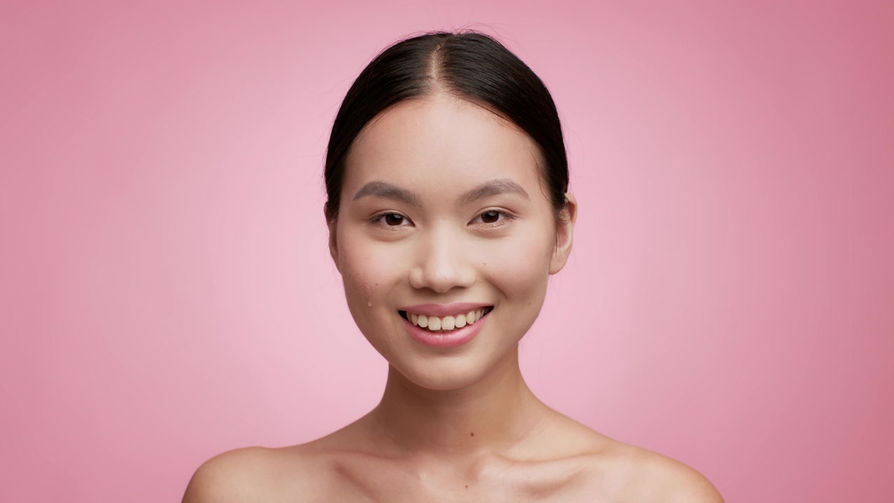 詳情圖-亞洲女性使用滴管在粉紅色背景上使用面部精華液