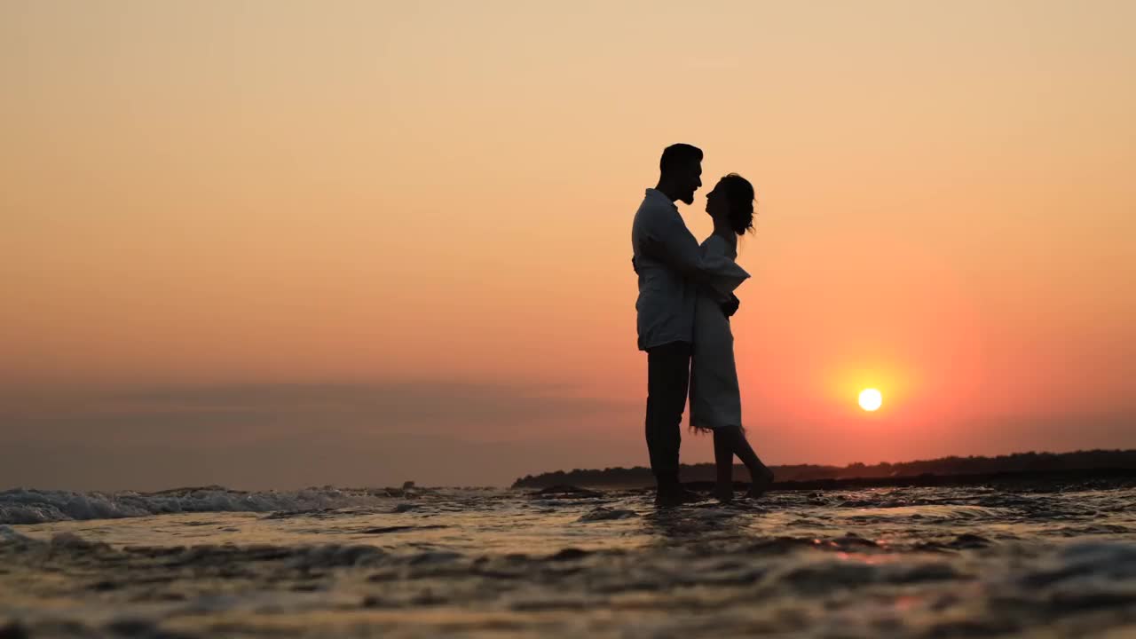夕阳下沙滩上一对浪漫情侣的剪影
