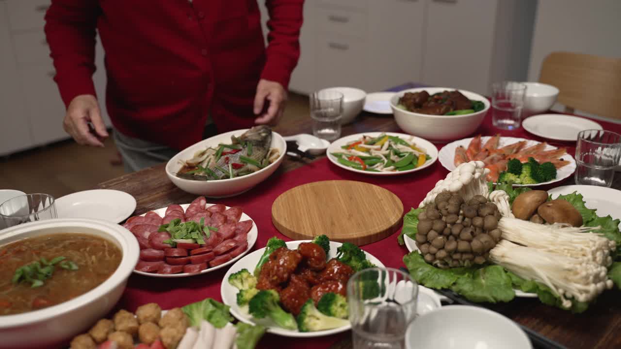 亚洲媳妇和大妈在家里准备年夜饭的时候，在桌子上端上一锅热汤。寓意“福”的柜体文字