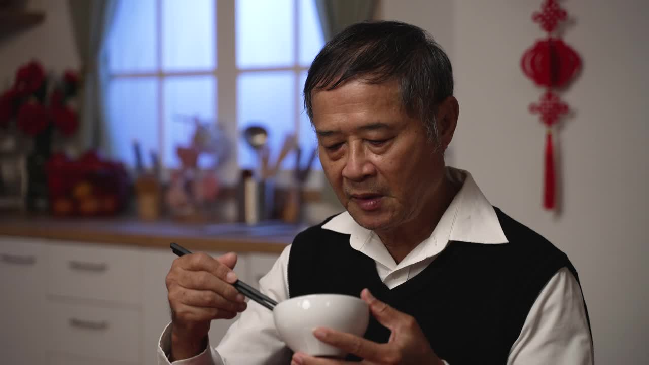 在家庭年夜饭上享用美味佳肴时，满意的亚洲老年男性祖父伸出大拇指并给予赞美的特写