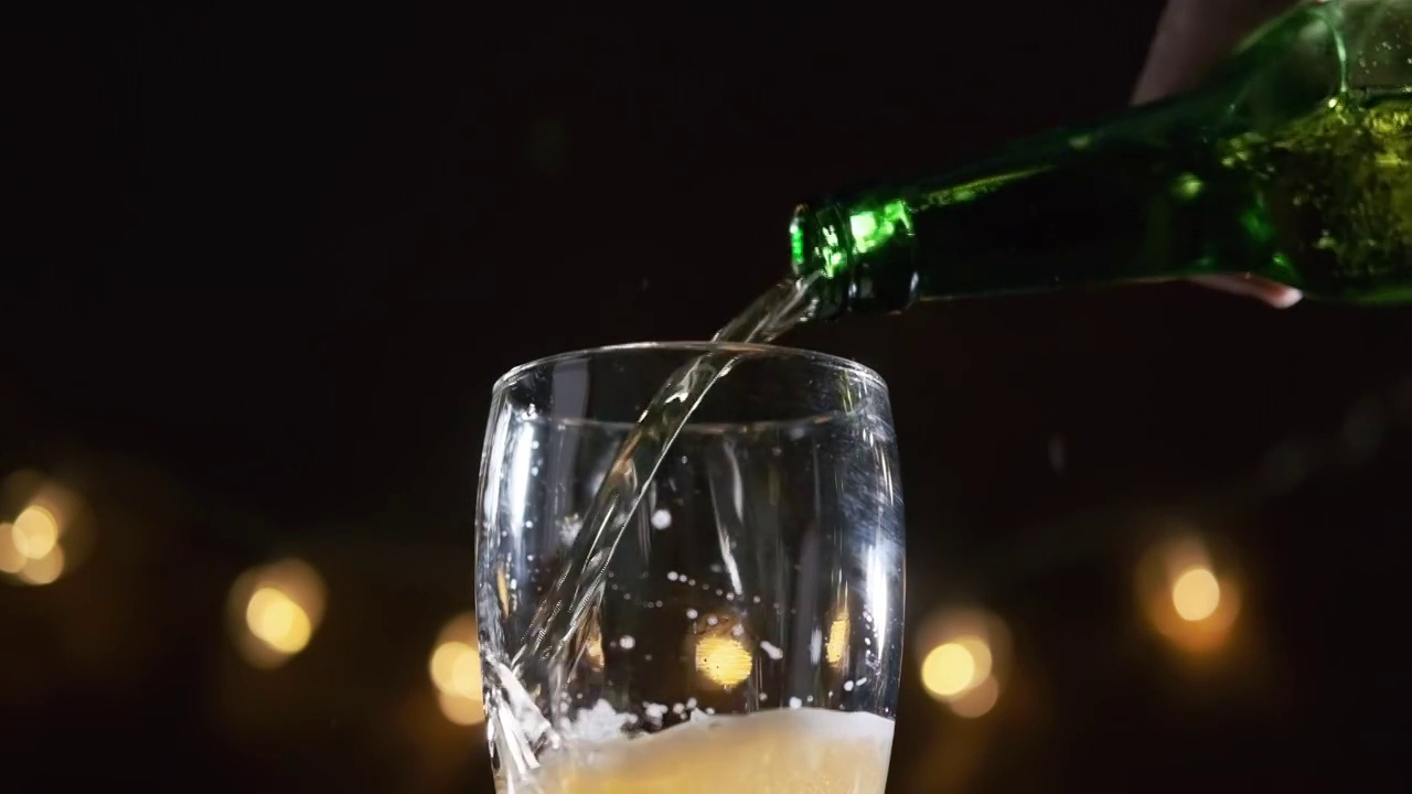 酒吧里往杯子里倒啤酒的男人的手