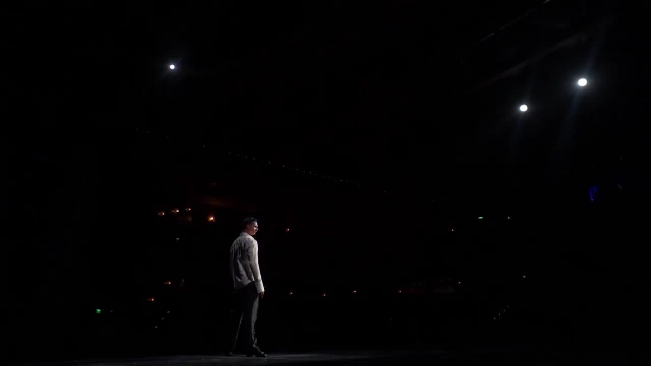 单人表演片段，交际舞舞者在舞台上的白色衬衫，裸露的躯干晒黑。从舞台到黑暗的大厅，后面的聚光灯。跨过去，跨步，跳步，弓步，链式旅行。远的距离
