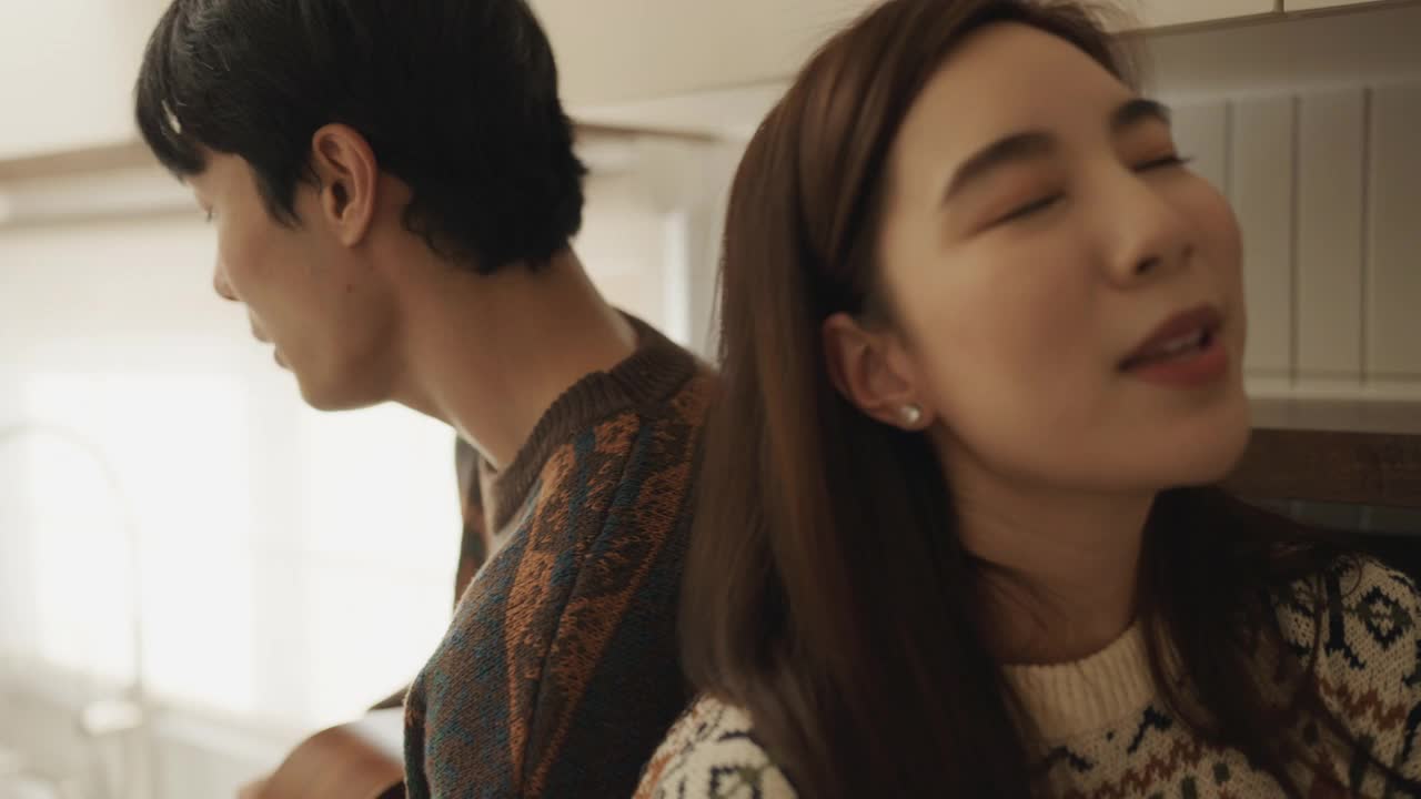 年轻夫妇在厨房里一起唱歌玩得很开心。