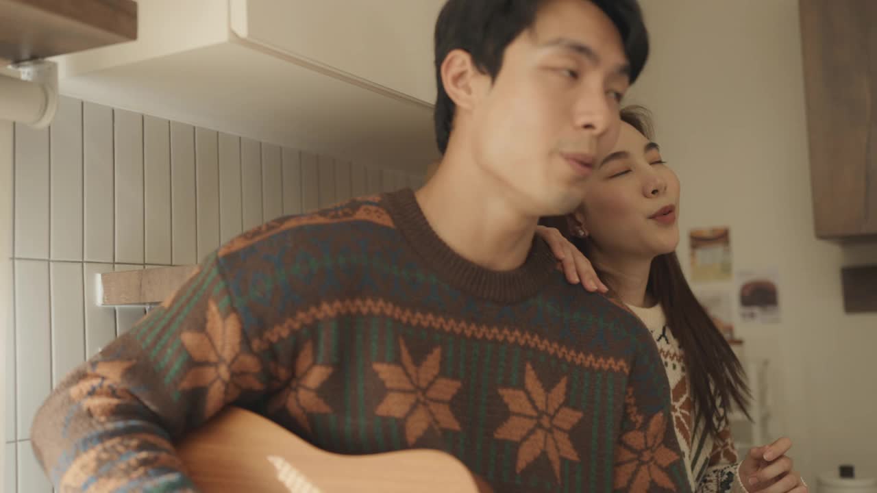 年轻夫妇在厨房里一起唱歌玩得很开心。
