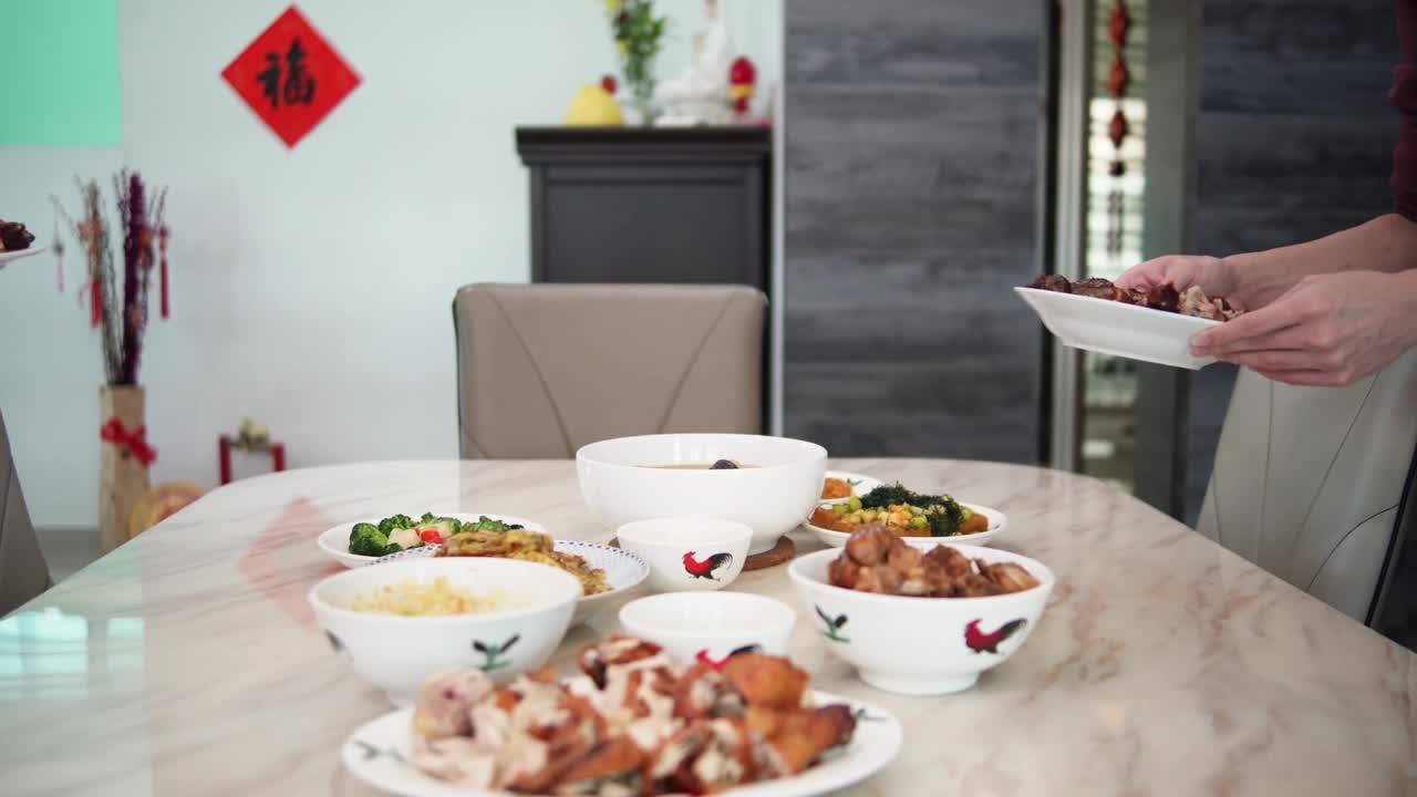 在中国新年期间，亚洲的中国年轻人和他的父亲把食物放在餐桌上