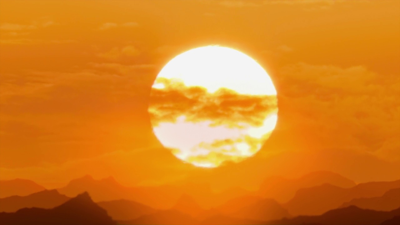 红橙红色的夕阳越过群山，炎热的天气，热的扭曲