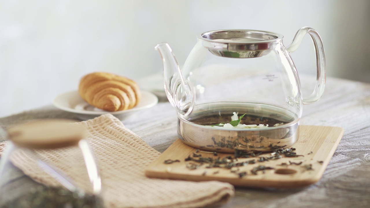 女士为早餐准备绿茶。用茉莉花冲泡绿茶的过程。手把茉莉花