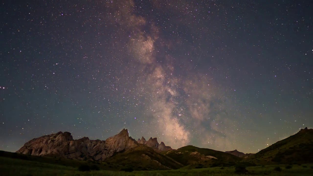 在群山的衬托下，银河在夜空中运动。