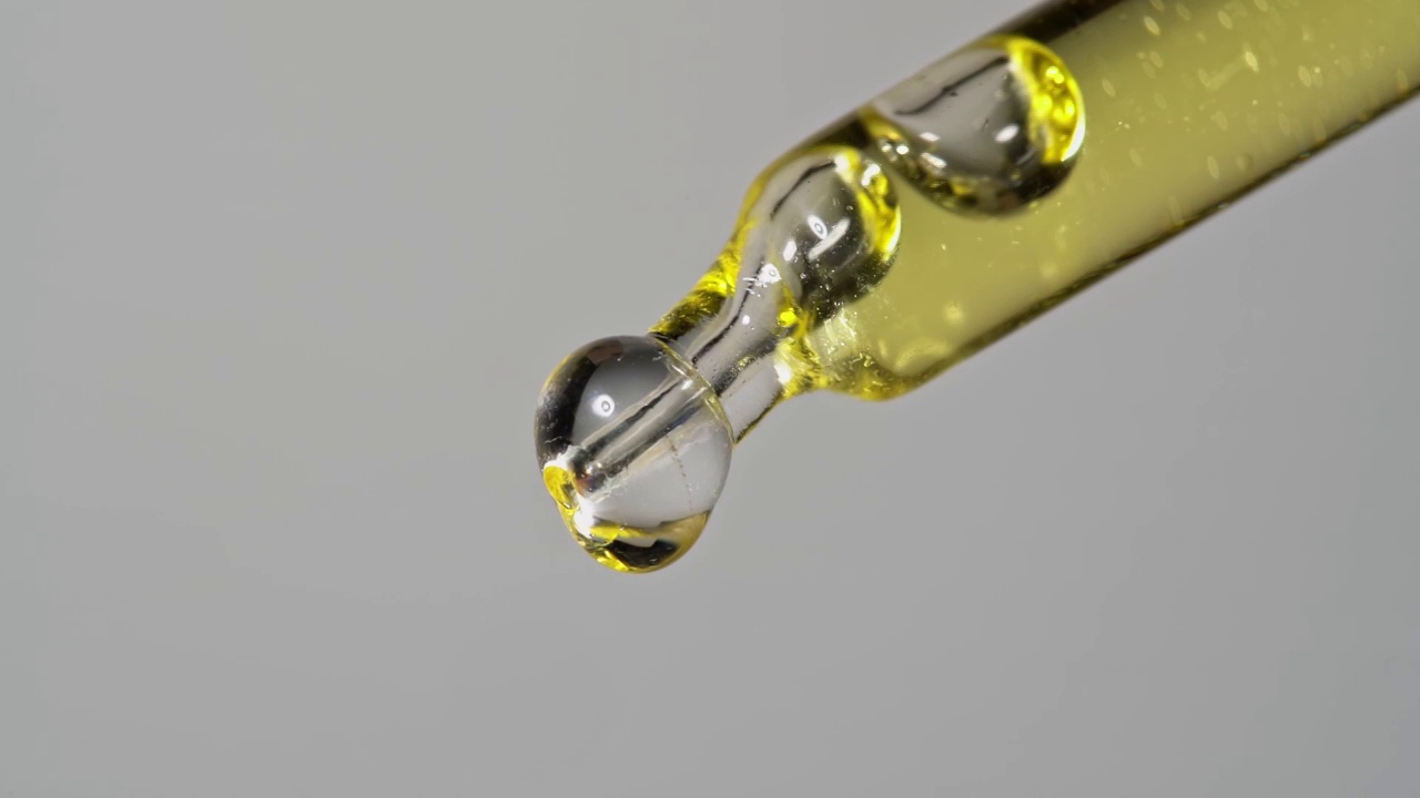 油萃取物从玻璃移液管滴下，用于化学反应和芳香疗法。关闭宏。