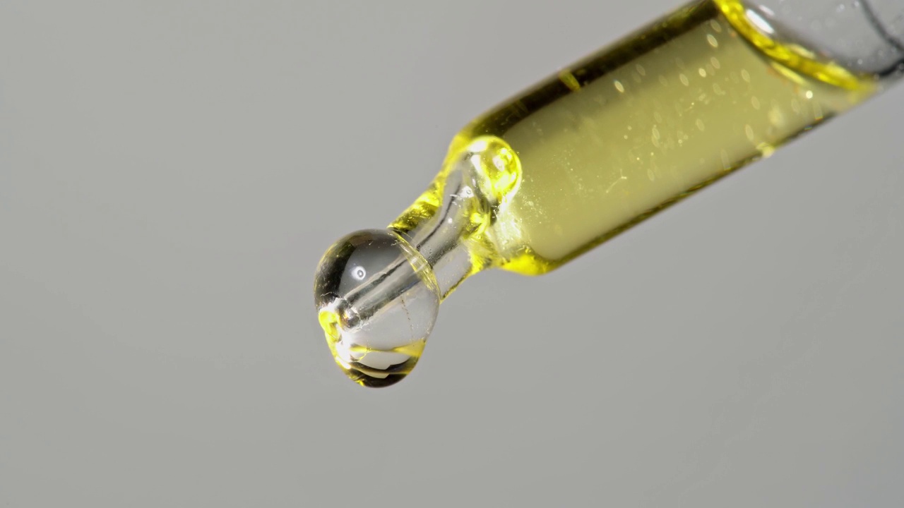 油萃取物从玻璃移液管滴下，用于化学反应和芳香疗法。关闭宏。