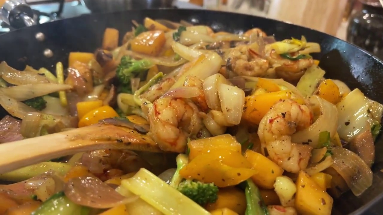 虾和芒果炒菜在家庭厨房准备食物切，剥皮，切丁搅拌新鲜的有机水果，蔬菜和肉类视频系列