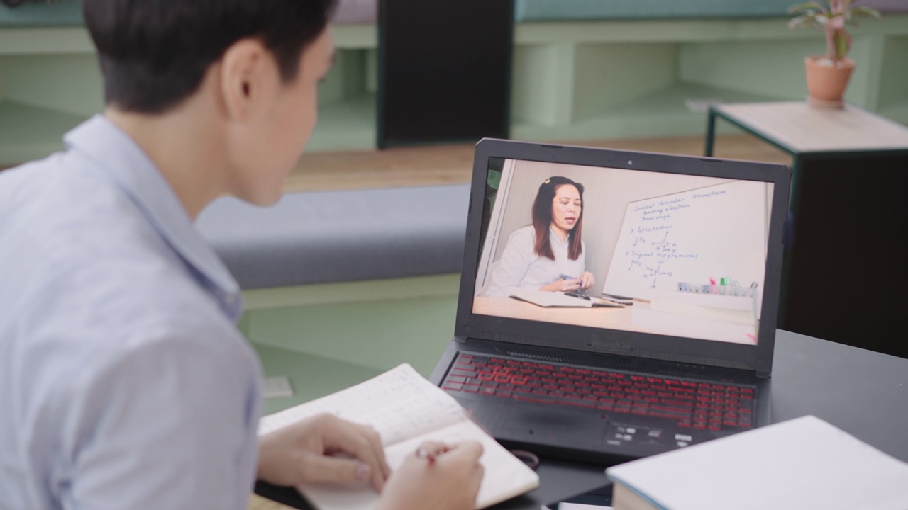 回头看:千禧一代的男大学生在网上学习化学，而老师在笔记本电脑屏幕上讲解化学键课，并在白板上书写