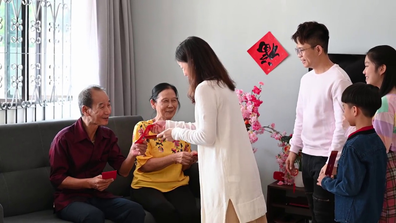 中国农历新年的第一天，亚洲老人在家里给他们的孩子和孙子孙女发红包。