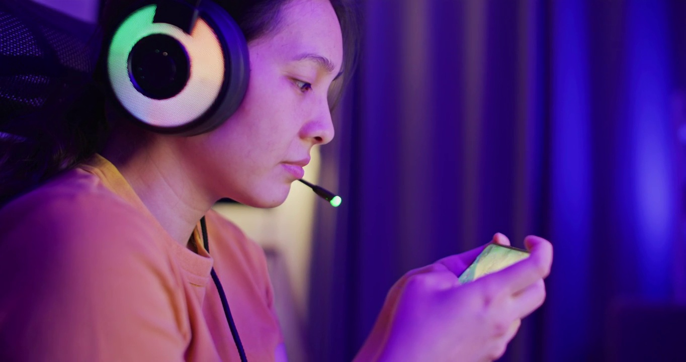 详情图-亚洲女性在家中客厅用智能手机玩网络游戏
