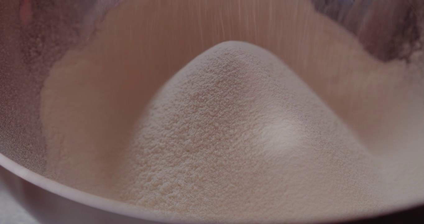 用滤网筛面粉。正在为烤牛角面包准备原料的妇女。
