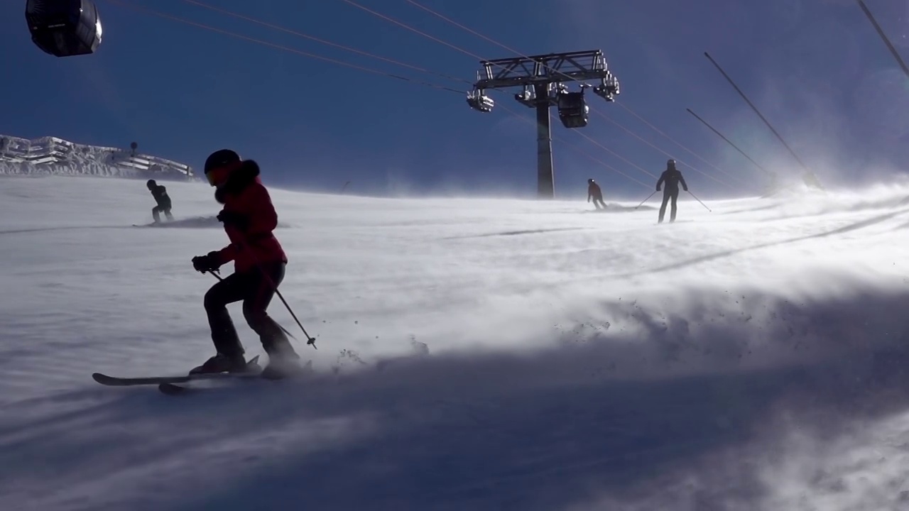 阳光滑雪坡和暴风雪上的滑雪者。慢动作