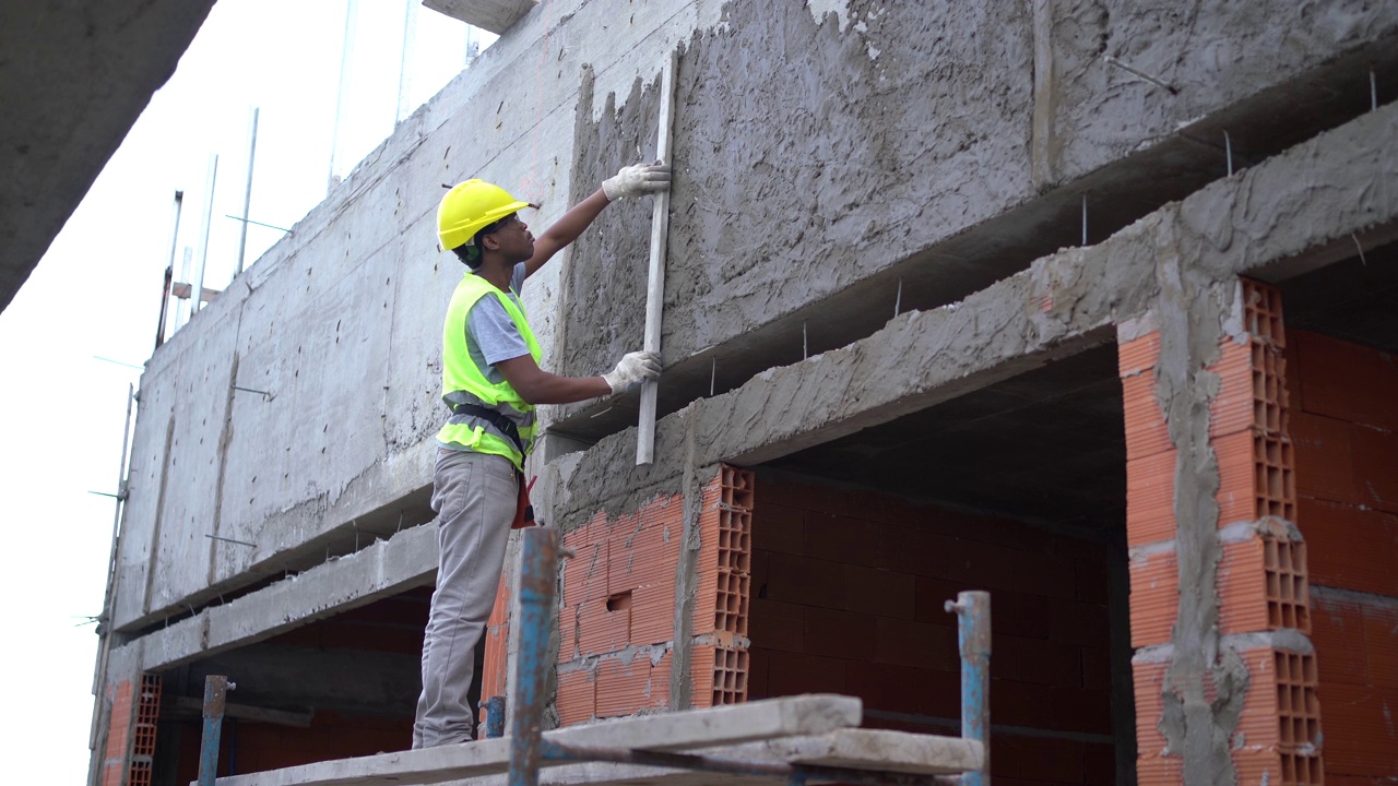 石匠工人用平板机给建筑外立面抹灰