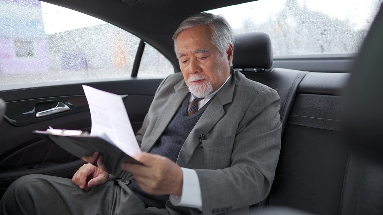 詳情圖-4K亞洲資深商人坐在車后座寫商業計劃