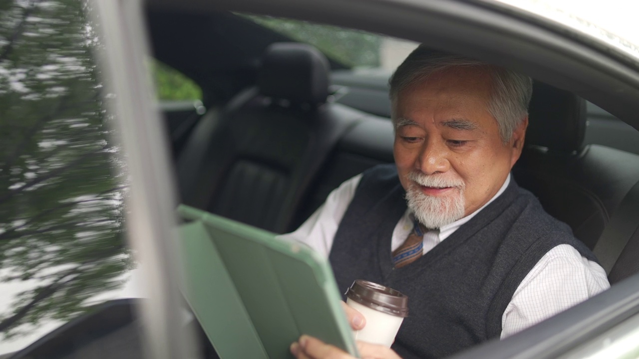 詳情圖-4K亞洲資深商人坐在汽車后座，一邊喝著熱咖啡，一邊在數(shù)碼平板電腦上工作