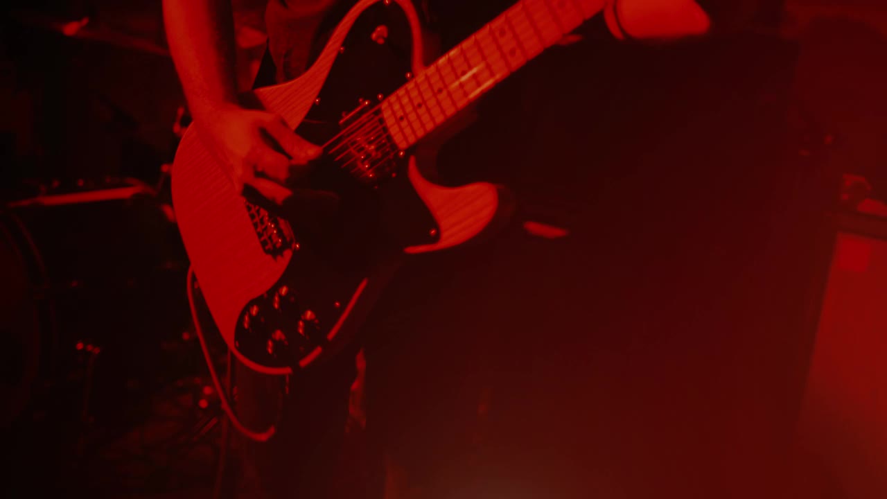 摇滚吉他手在舞台灯光下的现场表演中演奏吉他