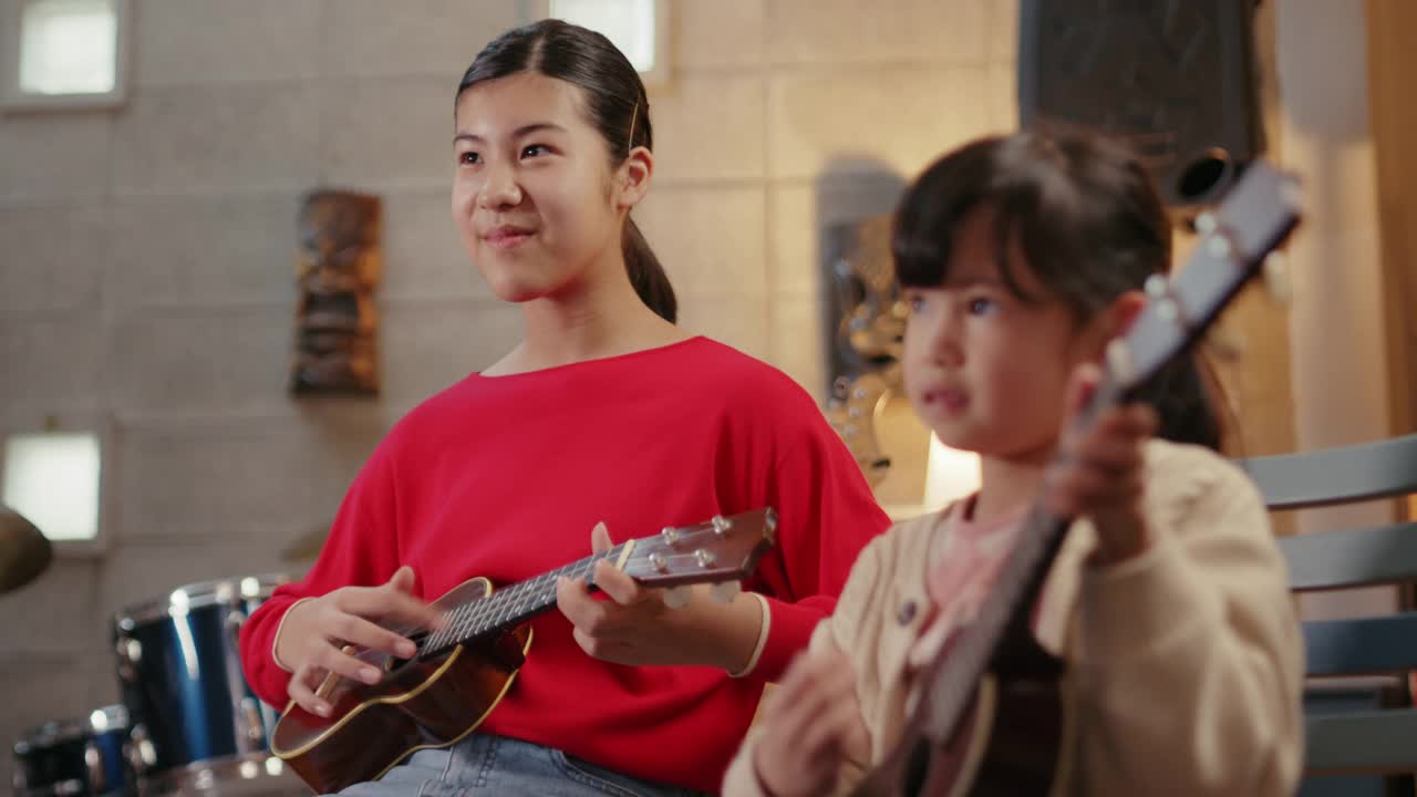 两个年轻女孩一起学习弹尤克里里