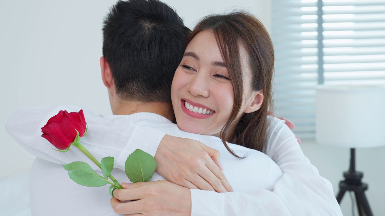 詳情圖-亞洲青年驚喜送玫瑰給美麗的女友。迷人浪漫的新婚男女坐在床上，一起享受慶祝周年紀(jì)念日和情人節(jié)