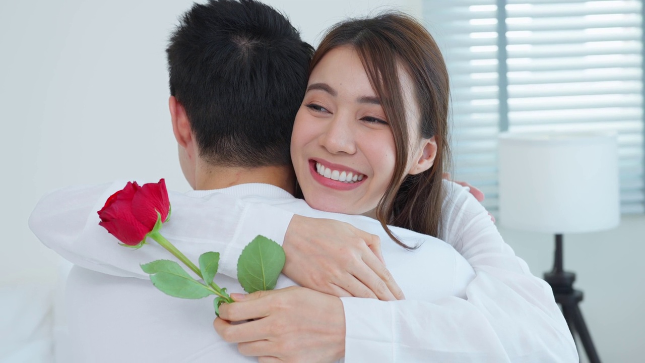詳情圖-亞洲青年驚喜送玫瑰給美麗的女友。迷人浪漫的新婚男女坐在床上，一起享受慶祝周年紀(jì)念日和情人節(jié)