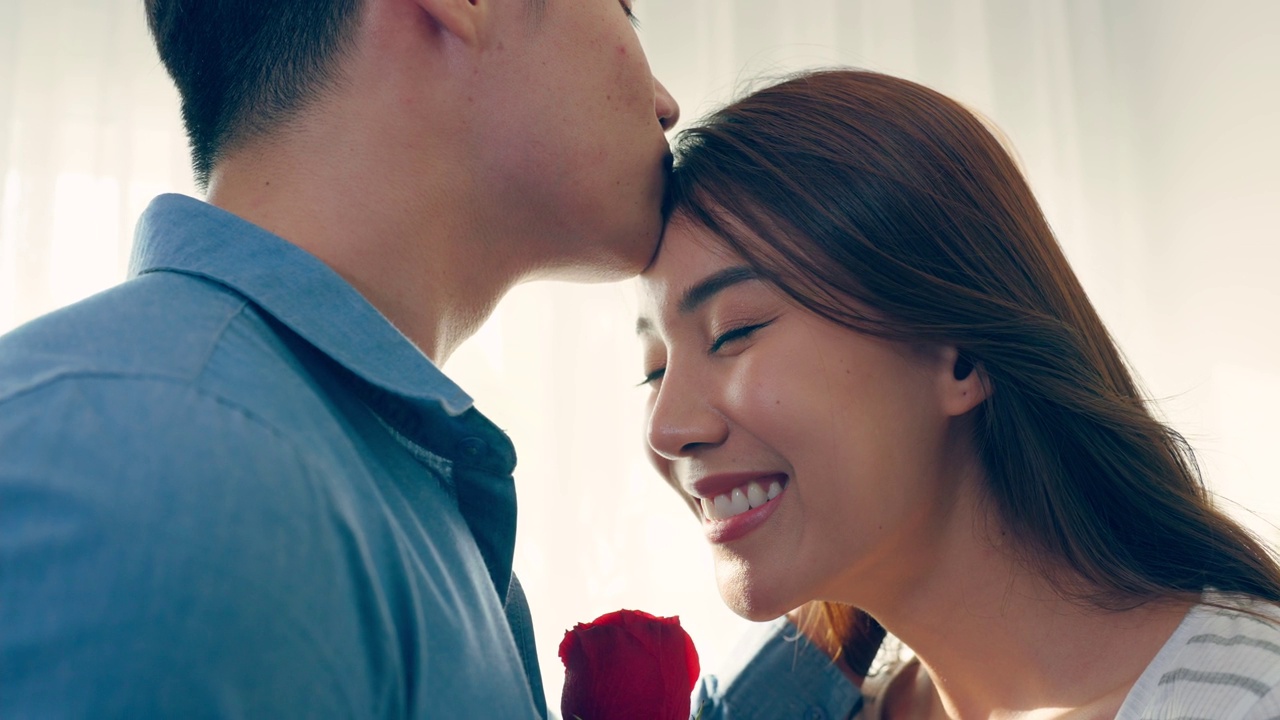 詳情圖-亞洲青年驚喜送玫瑰給美麗的女友。迷人浪漫的新婚男女花時間在房子里一起慶祝周年紀(jì)念日和情人節(jié)。