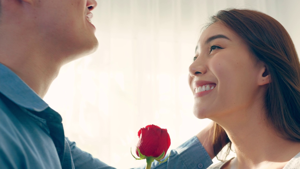 詳情圖-亞洲青年驚喜送玫瑰給美麗的女友。迷人浪漫的新婚男女花時間在房子里一起慶祝周年紀(jì)念日和情人節(jié)。