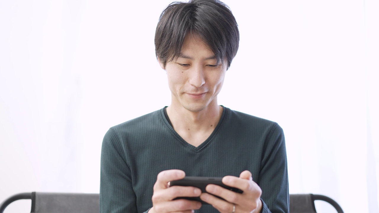 亚洲男子在智能手机上看视频